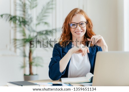 Сток-фото: Portrait Of Happy Redhaired Woman Employee In Optical Glasses Has Satisfied Expression Works With