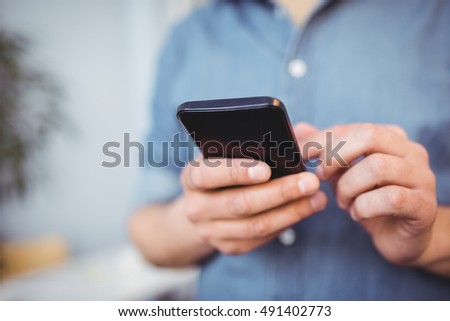 Foto stock: Midsection Of Businessman Texting On Cellphone At Creative Office