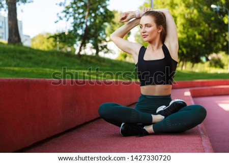 Stock photo: Photo Of Fitness Girl 20s In Tracksuit Stretching Her Arms Duri