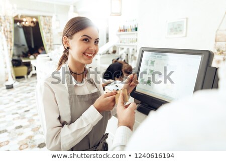 Foto stock: Female Staff Using Credit Card Terminal At Cash Counter