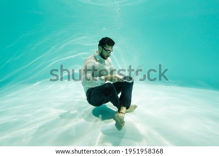 Foto stock: Young Man Using Laptop In Pool Of Light