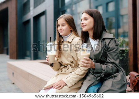 Zdjęcia stock: Happy Girl And Her Mother In Trenchcoats Having Milk Cocktails Outdoors