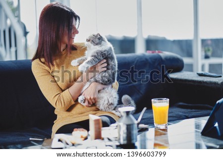 Foto stock: Young Woman Having A Mediterranean Breakfast Seated At Her Sofa And With Her Cat And Eats Healthy Tr