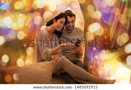 Stock photo: Happy Couple With Smartphone In Kids Tent At Home