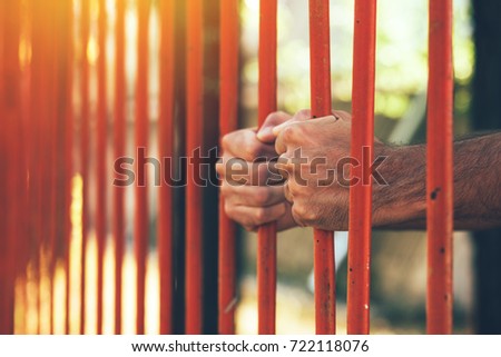 Stock photo: Male Hands Behind Prison Yard Bars