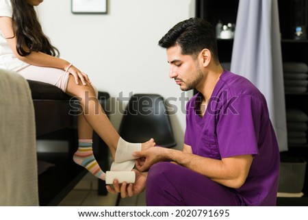 ストックフォト: Physiotherapist Putting Bandage On Injured Feet Of Girl Patient