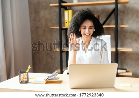Stock photo: Glad Young African American Woman Sits In Front Of Modern Computer Makes Project Work Has Many Pap