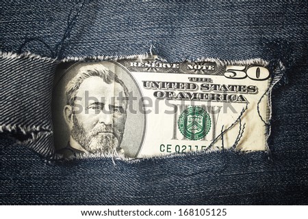 Foto stock: Fifty Dollars Bill Through Torn Blue Jeans Texture