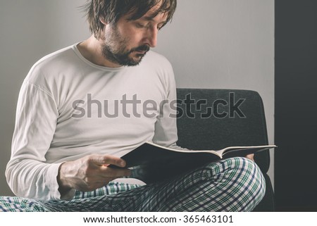 Stock fotó: Man Reading Magazine Early In The Morning Wearing Pajamas