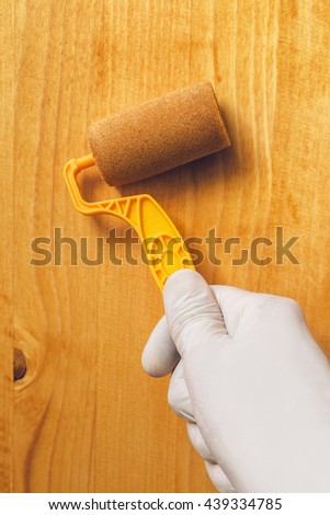 Stock photo: Hand With Paint Roller Applying Acrylic Lacquer On Wooden Board