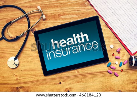 Foto stock: Health Insurance Title On Tablet Computer Placed On Doctors Desk