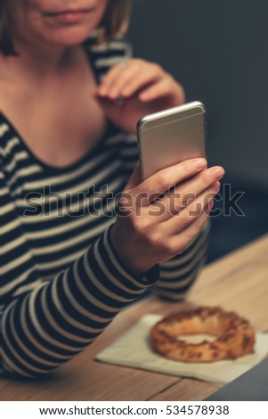 Stock fotó: Woman Eating Sesame Bagel And Using Mobile Phone