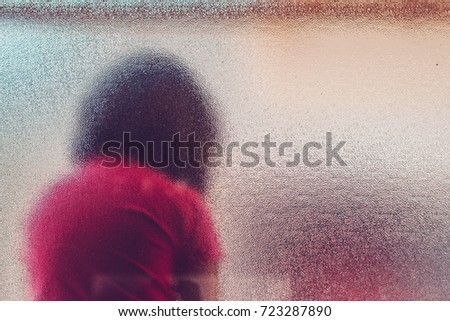 Stockfoto: Silhouette Of Unrecognizable Sad Autistic Girl Behind Stained Gl