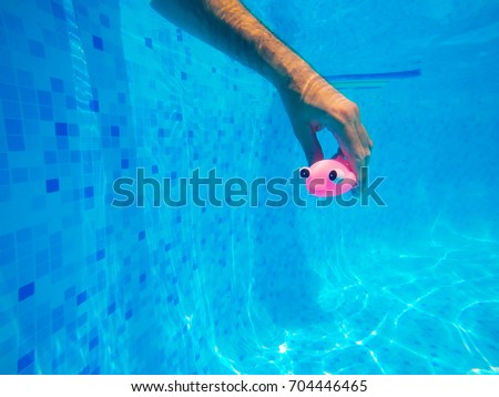 Stok fotoğraf: Man Playing With Generic Rubber Fish Toy In Swimming Pool