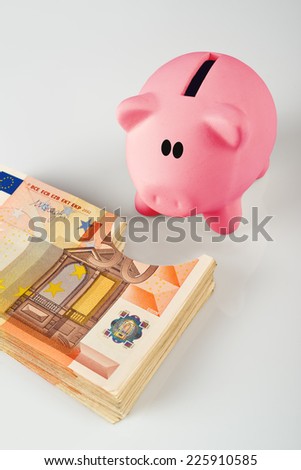 Foto stock: Piggy Coin Bank Eating Fifity Euro Pile