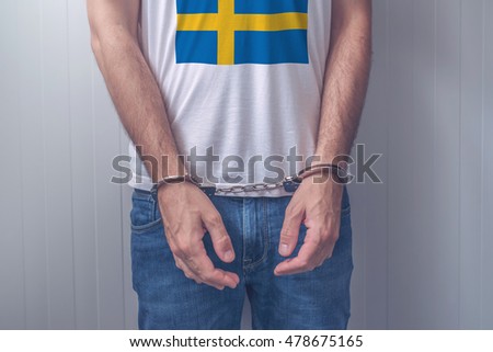 [[stock_photo]]: Arrested Man With Cuffed Hands Wearing Shirt With Swedish Flag