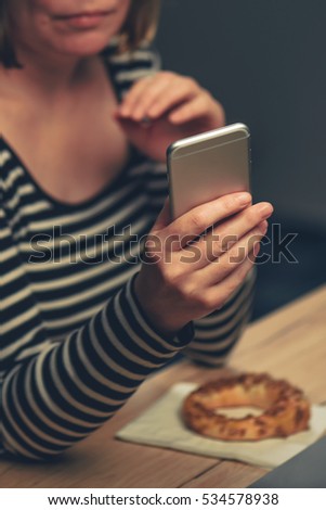 Сток-фото: Woman Eating Sesame Bagel And Using Mobile Phone