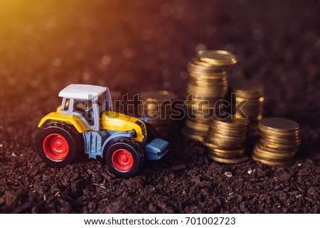 Foto d'archivio: Agricultural Tractor Toy And Golden Coins On Fertile Soil Land
