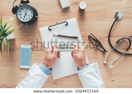 [[stock_photo]]: Male Doctor Holding Unlabeled Generic Tablets