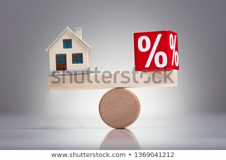 Foto stock: Miniature House And Percentage Block On Wooden Seesaw