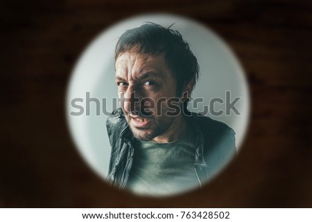 Stockfoto: Angry Man At The Door Viewed Through Spy Hole