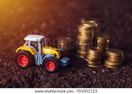 Stok fotoğraf: Agricultural Tractor Toy And Golden Coins On Fertile Soil Land