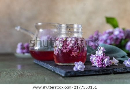 Сток-фото: Lilac Flowers Sugar And Syrup Essential Oil With Flower Blossoms In Glass Jar Grey Stone Background