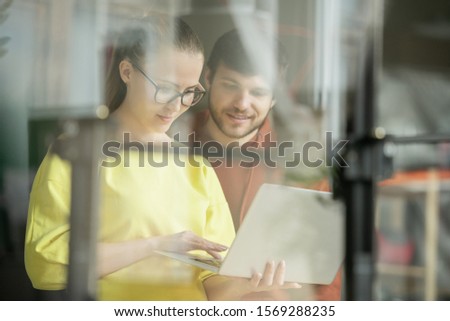 Zdjęcia stock: Young Businessman Looking At Display Of Laptop Held By His Colleague
