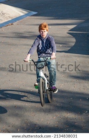 Foto d'archivio: Joung Red Haired Boy Jumps With His Bmx Bike At The Skate Park