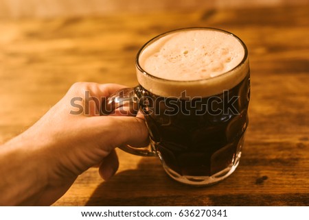 Foto stock: Man Drinking Dark Beer In British Dimpled Glass Pint Mug