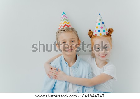 Stock photo: Lovey Red Haird Girl Embraces With Love Her Older Brother Congratulates With Birthday Wear Cone Pa
