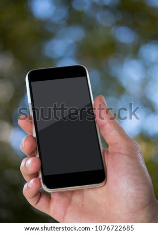 商業照片: Hand With Phone Against Blurry Leaves