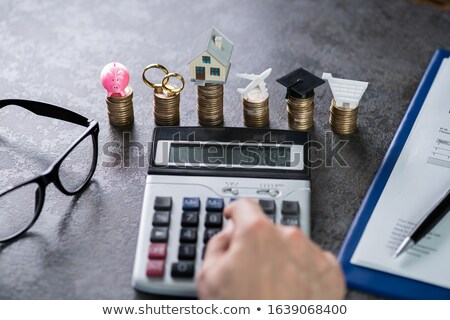 Stock foto: Man Calculating Expenses In Front Of Stacked Coins