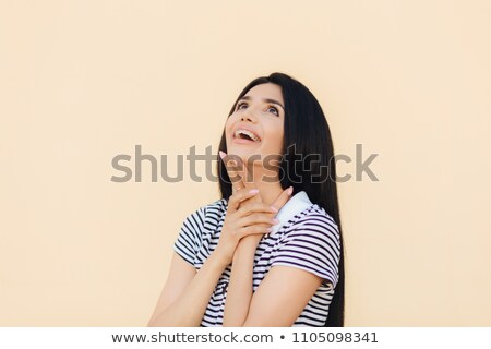 Foto stock: Joyful Gorgeous Young Female Model Looks Happily Upwards And Keeps Hand Under Chin Notices Somethin