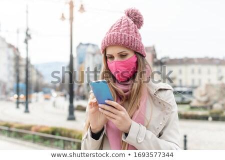 Foto stock: Anxious Woman Wearing Corona Mask Checking News On Her Phone