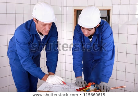 [[stock_photo]]: Experienced Tradesman Teaching His Apprentice How To Read A Blueprint