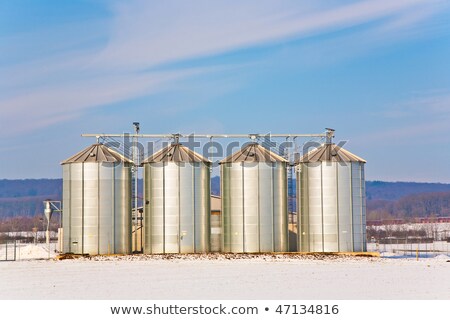 Stockfoto: Landscape With Silo And Snow White Acre With Blue Sky