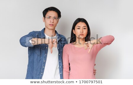 Stock foto: Young Guy Showing Thumbs Down Sign Over Gray Background