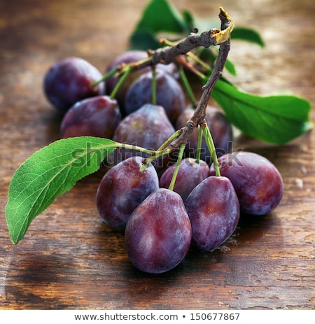 Imagine de stoc: Fresh Plums With Green Leaves On Wooden Rustic Background