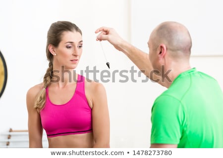 Foto stock: Instructor Hypnotizing Woman With Pendulum Tool