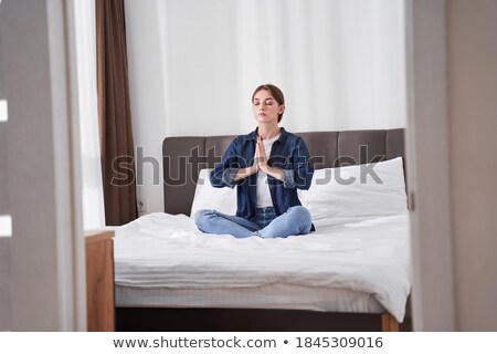 Stockfoto: Woman Sitting In Praying Position On Bed