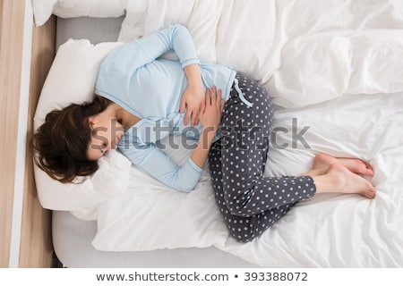 Stock photo: Woman Suffering From Stomach Ache Lying At Home