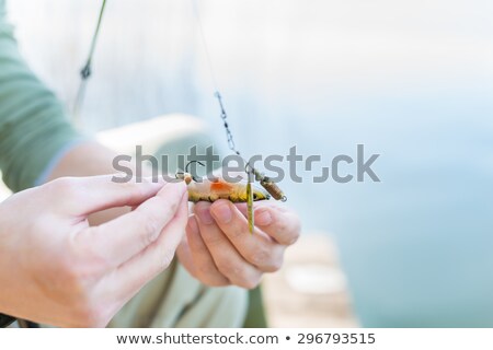 [[stock_photo]]: Angler Fixing Lure At Hoof Of Fishing Rod