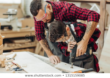 Foto d'archivio: Father And Son With Drill Working At Workshop