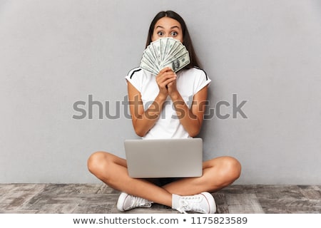 Сток-фото: Young Woman Sitting Isolated Over Grey Background Using Laptop Computer Holding Money Covering Face
