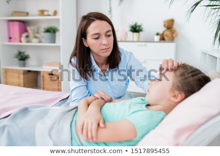Stock photo: Sad Careful Mother Sitting By Bed Of Sick Little Girl In Fever