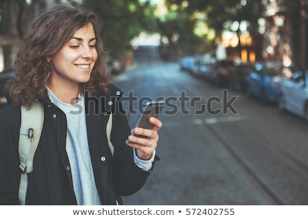 Foto stock: Young Woman Using Mobile Phone Walking On Street