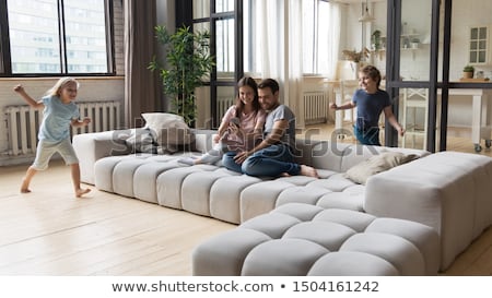 Foto stock: Cute Friends Sitting On A Sofa With A Mobile In A Living Room