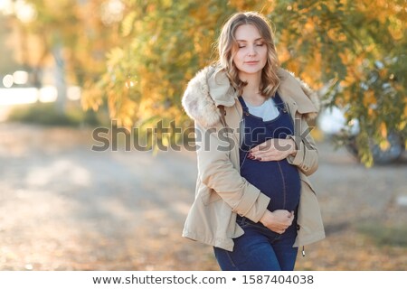 Stock foto: A Woman In Autumn In A Warm Jacket On A Walk In The Afternoon In The Garden