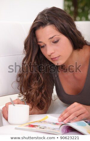 [[stock_photo]]: Young Woman Enjoying Peaceful Moment Skimming Through Catalogue